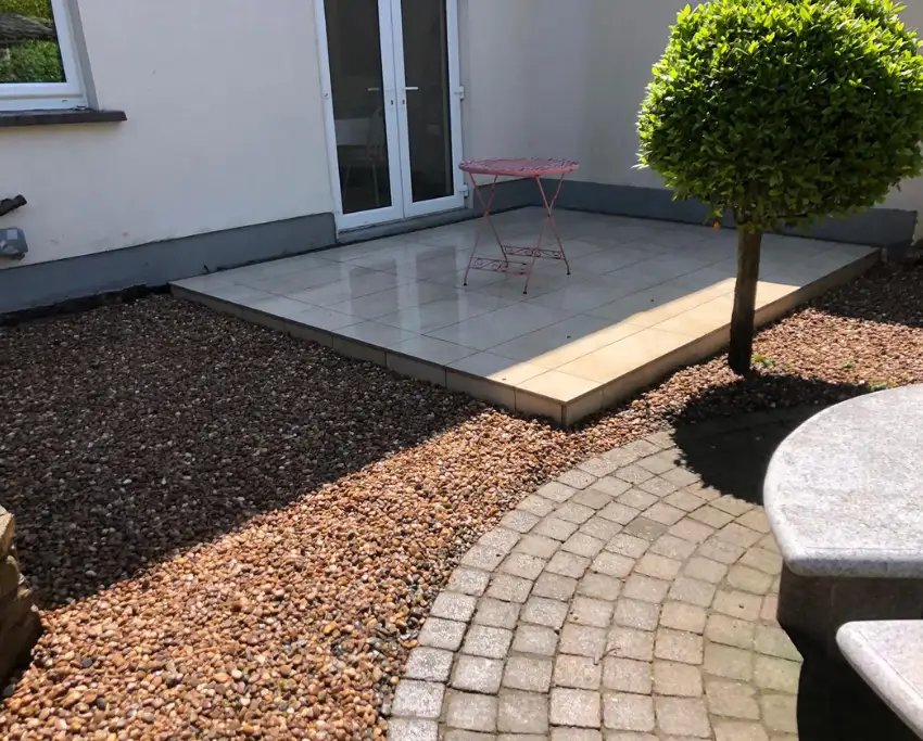 Modern porcelain patio framed by cobble lock and gravel